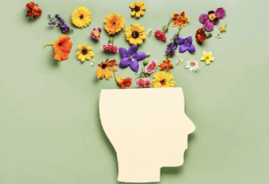 Silhouette of a human head with colorful flowers emerging from the top, symbolizing mental health, growth, and emotional well-being